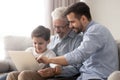 Happy grandfather and father teaching little boy to use laptop Royalty Free Stock Photo