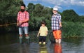 Happy grandfather and grandson are fishing on the river. Father, son and grandfather relaxing together. Men hobby Royalty Free Stock Photo