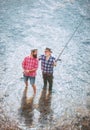 Happy grandfather and grandson with fishing rods on river berth. Happy family concept - father and son together. Fly Royalty Free Stock Photo