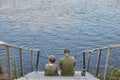 Happy grandfather and grandson fishing together, sitting on wooden placing near river, holding fishing rod in hands, enjoying Royalty Free Stock Photo