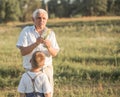 Happy grandfather and grandson walking at summer meadow.  Cute boy gives flowers his old grandpa Royalty Free Stock Photo