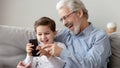 Happy grandfather and little grandson using phone, have fun together Royalty Free Stock Photo