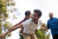 Happy grandfather looking at man giving piggy backing to son Royalty Free Stock Photo