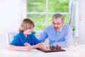 Happy grandfather playing chess with his grandson