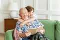 Happy grandfather sitting on couch with adorable kid boy