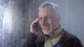 Happy grandfather talking on phone and smiling, family communication, mobile app Royalty Free Stock Photo