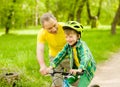 Happy grandfather teaches his grandson to ride a bike Royalty Free Stock Photo