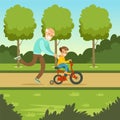 Happy grandfather teaching kid boy to ride the bicycle