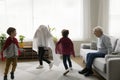 Happy grandfather watching three boys in homemade super hero costumes