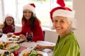 Happy grandmother, granddaughter and adult daughter wearing santa hats sitting at christmas table Royalty Free Stock Photo