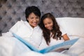 Happy grandmother and granddaughter reading book on bed Royalty Free Stock Photo