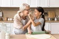 Happy grandmother and granddaughter touching faces with floury hands