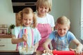 Happy grandmother with her grandchildren having fun during baking muffins and cookies Royalty Free Stock Photo