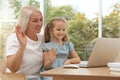 Happy grandmother and her granddaughter having video chat via laptop together at home Royalty Free Stock Photo