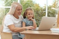 Happy grandmother and her granddaughter using laptop together at home Royalty Free Stock Photo