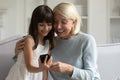 Happy grandmother and little granddaughter using phone together, having fun Royalty Free Stock Photo