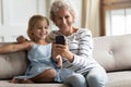 Happy grandmother and small grandchild using cellphone at home Royalty Free Stock Photo