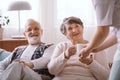 grandmother taking a cup of tea from her caregiver in the nursing home