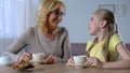 Happy grandmother talking and drinking tea with little cute granddaughter, love Royalty Free Stock Photo