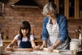 Happy grandmother teaching focused grandchild to knead roll dough Royalty Free Stock Photo