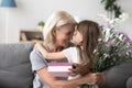 Happy grandmother thanking cute granddaughter for flowers and gi Royalty Free Stock Photo