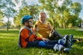 Happy grandpa and grandchild eating ice-cream after roller skating