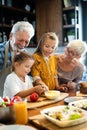 Happy grandparents with grandchildren making breakfast in kitchen Royalty Free Stock Photo
