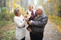 Happy grandparents with little baby granddaughter in beautiful autumn park