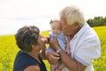 Happy grandparents with little baby granddaughter enjoying moment in beautiful yellow field