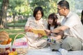 A happy grandparents are telling a fairytale to their lovely granddaughter while picnicking together Royalty Free Stock Photo