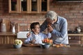 Happy grandson and grandfather cooking salad for lunch at home