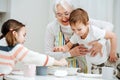 Happy granny holding her grandson, standing on a stool, reaching for the food