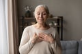 Happy grateful older lady posing at home with closed eyes