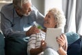 Smiling mature woman using digital computer tablet, chatting with husband. Royalty Free Stock Photo