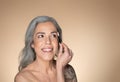 Happy grey-haired senior woman brushing eyebrows with brush and smiling, enjoying beauty routine and cosmetics product Royalty Free Stock Photo