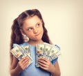 Happy grimacing doubt thinking kid girl holding money in the han