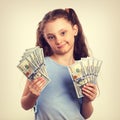 Happy grimacing doubt thinking kid girl holding money in the han