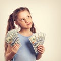 Happy grimacing fun thinking kid girl holding money in the hands