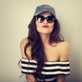 Happy grimacing young woman in sunglasses and blue baseball cap Royalty Free Stock Photo