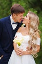 happy groom and bride in traditional wedding clothes kiss and joke in park Royalty Free Stock Photo