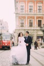 Happy groom and bride walking the streets of the old city with tram on background Royalty Free Stock Photo