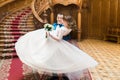 Happy groom carrying his wife with bouquet near big wooden stairs at old vintage house Royalty Free Stock Photo