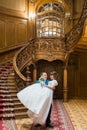 Happy groom carrying his wife with bouquet near big wooden stairs at old vintage house Royalty Free Stock Photo