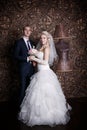 Happy groom and the charming bride with a bouquet from roses in studio