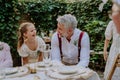 Happy groom talking and smiling with his little daughter during outdoor wedding party. Royalty Free Stock Photo