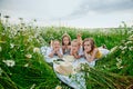 A happy group of children lies in a field of camomiles at sunset in the summer. Boys and girls lie on a blanket in nature, a