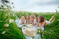 A happy group of children lies in a field of camomiles at sunset in the summer. Boys and girls lie on a blanket in nature, a