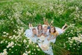 A happy group of children lies in a field of camomiles at sunset in the summer. Boys and girls lie on a blanket in nature, a Royalty Free Stock Photo