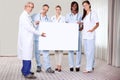 Happy group of doctors holding a blank placard Royalty Free Stock Photo