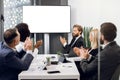 Happy group of five diverse multiethnic businesspeople clapping hands, while sitting at the table in modern office, in Royalty Free Stock Photo